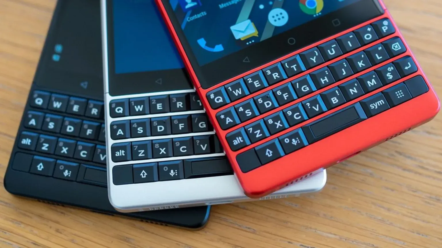 A BlackBerry phone with a physical keyboard on a desk