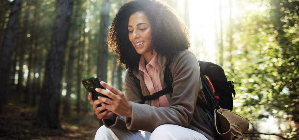 A hiker checking her phone on a wooded trail