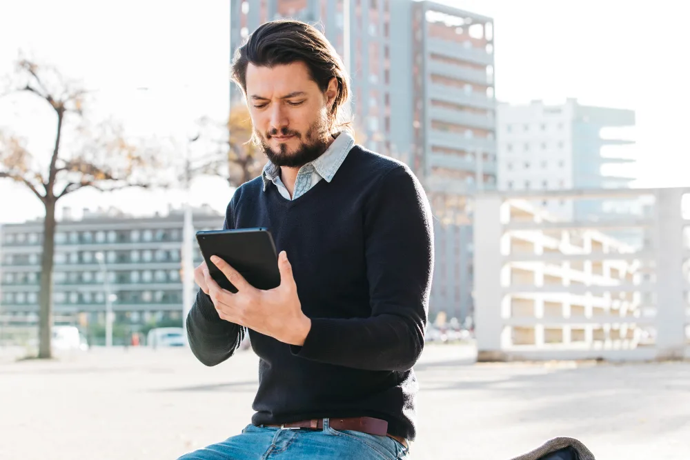 A man adjusting settings on his device outdoors in a city