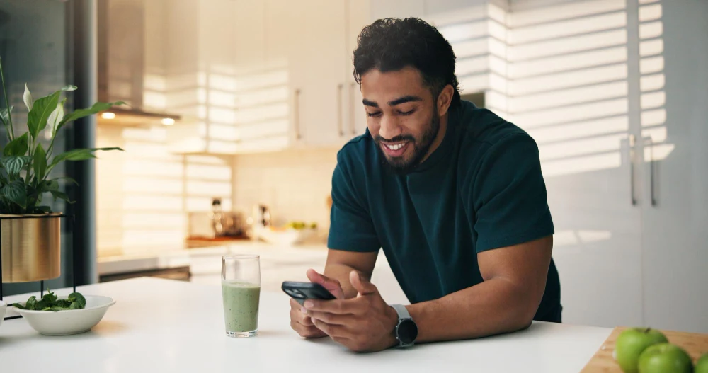 A man checking his phone at a kitchen counter