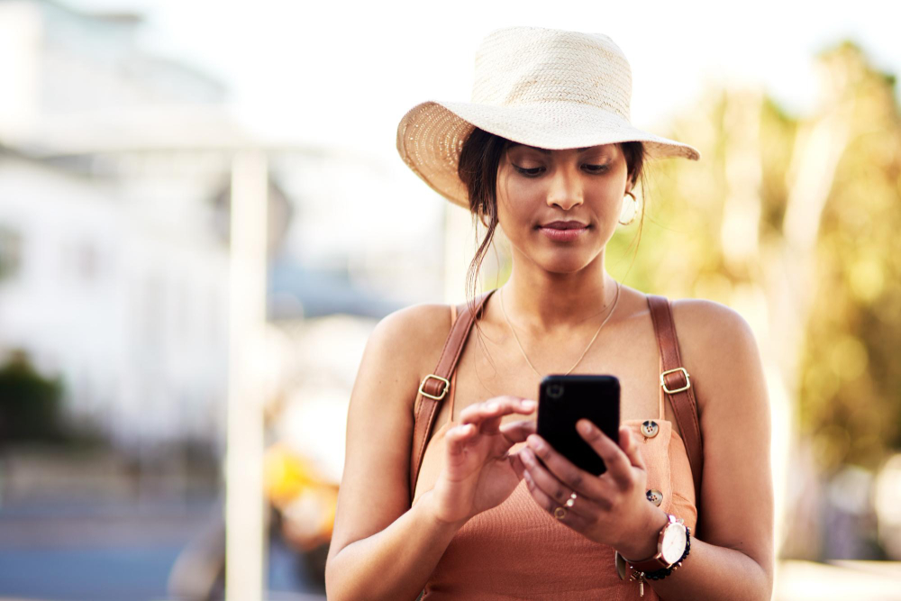 A woman in a sun hat checking her phone while travelling