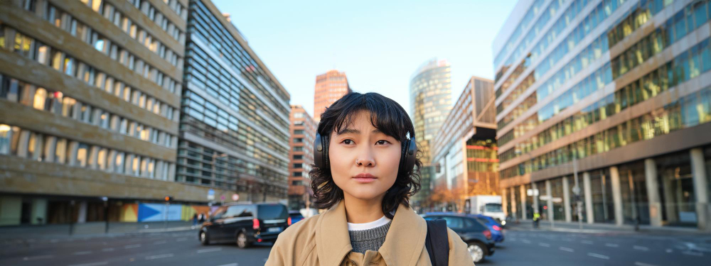 A woman in headphones standing on a city street