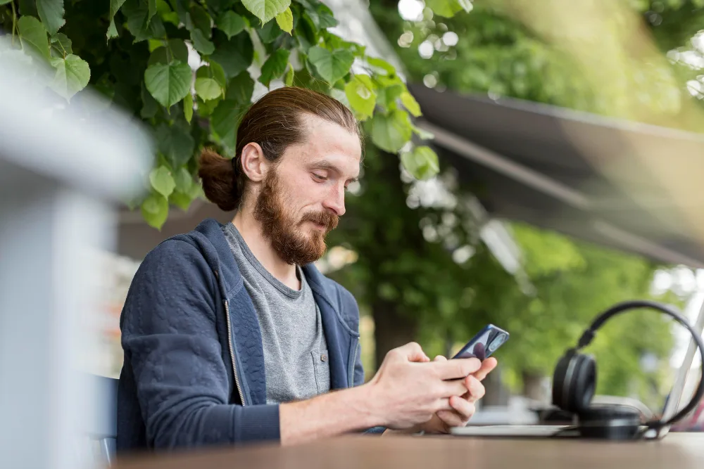A man checking his phone at an outdoor cafe table