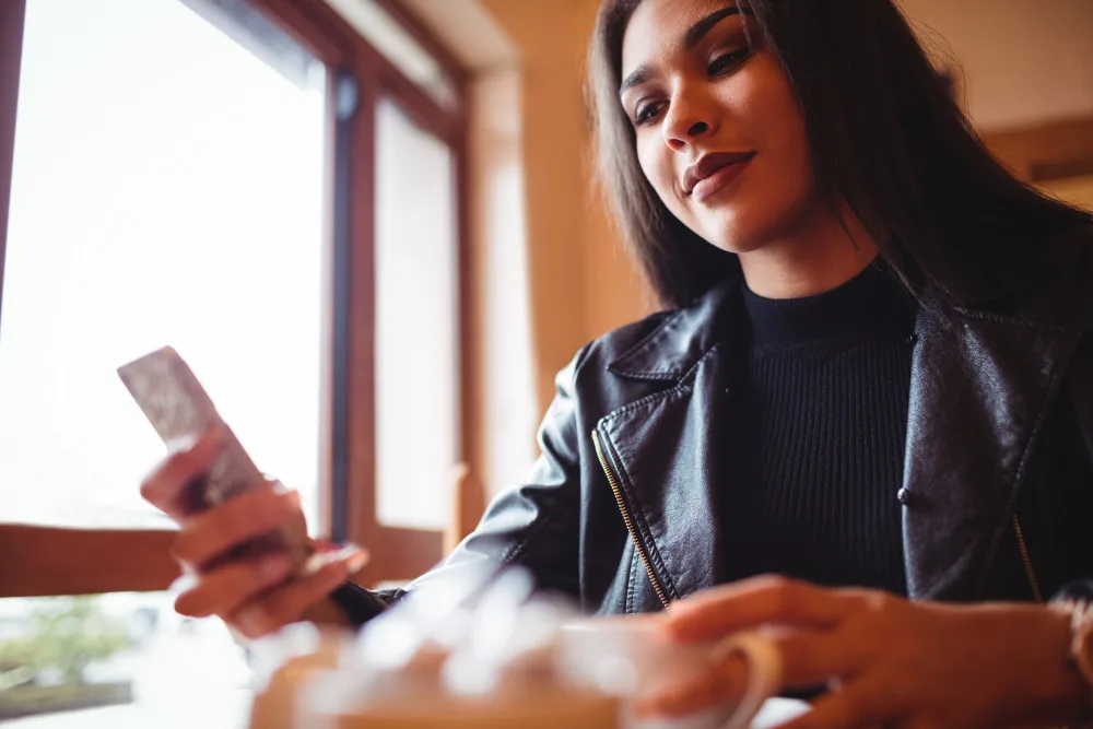 A woman checking her phone over coffee in a cafe